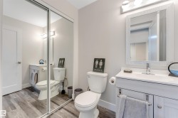 Modern bathroom featuring wood-finish flooring and a contemporary vanity with a white countertop - 