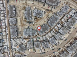 Aerial view of the residential area, featuring properties with multi-gabled roofs and paved driveways - 