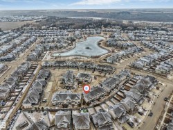 Aerial view of the community, featuring residential properties and a central pond - 