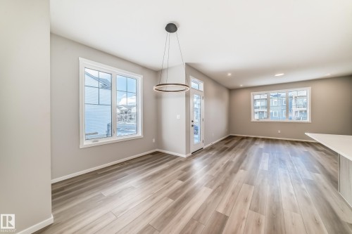 This inviting room features light-toned flooring, ample natural light from multiple windows, and a modern ceiling light fixture - 840 Stillwater Boulevard, Edmonton, AB - Indoor Photo Showing Other Room