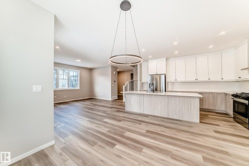 Open concept living space featuring light-toned flooring, a modern circular chandelier, and recessed lighting - 840 Stillwater Boulevard, Edmonton, AB - Indoor Photo Showing Kitchen With Upgraded Kitchen
