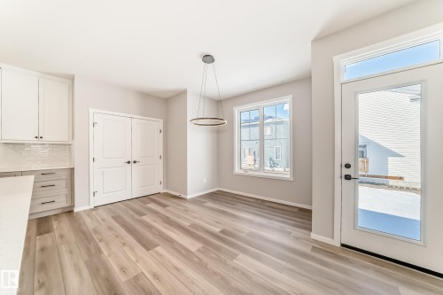 This bright space features light-toned flooring, white walls, and a modern ceiling light fixture - 840 Stillwater Boulevard, Edmonton, AB - Indoor