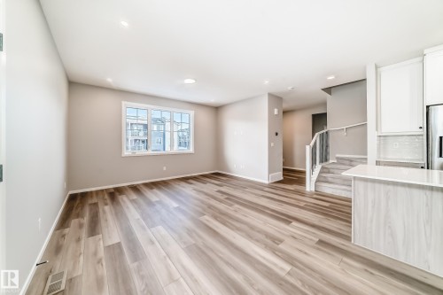 This inviting interior features light wood flooring and neutral wall tones, complemented by a large window providing natural light - 840 Stillwater Boulevard, Edmonton, AB - Indoor Photo Showing Other Room