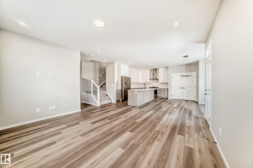 Spacious interior featuring wide plank flooring, recessed lighting, and a modern kitchen with a center island and stainless steel appliances - 840 Stillwater Boulevard, Edmonton, AB - Indoor Photo Showing Other Room