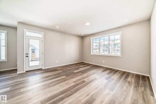 Living area featuring light wood-style flooring, neutral-toned walls, recessed lighting, and a large window providing natural light - 840 Stillwater Boulevard, Edmonton, AB - Indoor Photo Showing Other Room