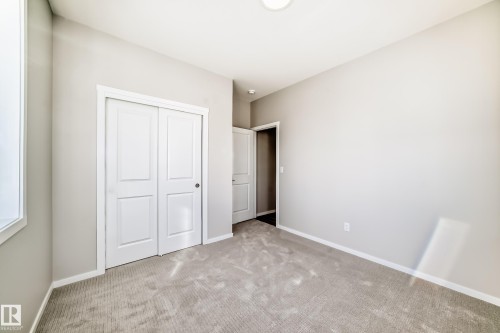 The property features a bright room with light gray walls, a window on the left, and light-colored carpeted flooring - 840 Stillwater Boulevard, Edmonton, AB - Indoor Photo Showing Other Room
