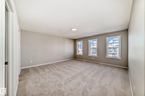 Spacious room featuring neutral carpeting, light-colored walls, and three windows providing natural light - 840 Stillwater Boulevard, Edmonton, AB - Indoor Photo Showing Other Room