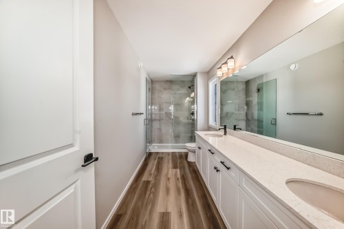 Bathroom featuring a double vanity with quartz countertops, a large mirror, and a glass-enclosed shower with tile surround - 840 Stillwater Boulevard, Edmonton, AB - Indoor Photo Showing Bathroom