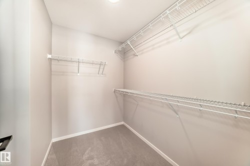 This walk-in closet features ample storage with white wire shelving, a light-colored carpet, and recessed lighting - 840 Stillwater Boulevard, Edmonton, AB - Indoor With Storage