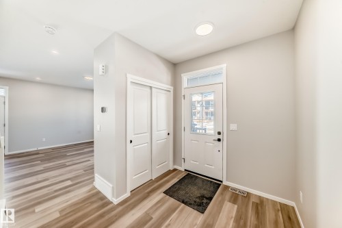 The property features an entryway with a white door, a transom window, and wood-look flooring - 840 Stillwater Boulevard, Edmonton, AB - Indoor Photo Showing Other Room