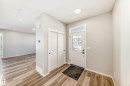 The property features an entryway with a white door, a transom window, and wood-look flooring - 840 Stillwater Boulevard, Edmonton, AB  - Indoor Photo Showing Other Room 