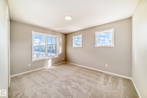 This room features neutral-toned walls, light-colored carpet, and a ceiling light fixture - 840 Stillwater Boulevard, Edmonton, AB - Indoor Photo Showing Other Room