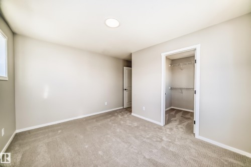 This neutral-toned room features light-colored carpeting, a window, a recessed ceiling light, and a closet with wire shelving - 840 Stillwater Boulevard, Edmonton, AB - Indoor Photo Showing Other Room