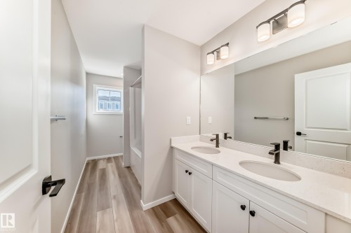 Bathroom featuring a double vanity with two undermount sinks, bronze faucets, and a large mirror with overhead lighting - 840 Stillwater Boulevard, Edmonton, AB - Indoor Photo Showing Bathroom