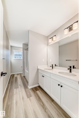 Spacious bathroom featuring a double vanity with white cabinetry, light-colored countertops, dual sinks, and matte black faucets - 840 Stillwater Boulevard, Edmonton, AB - Indoor Photo Showing Bathroom