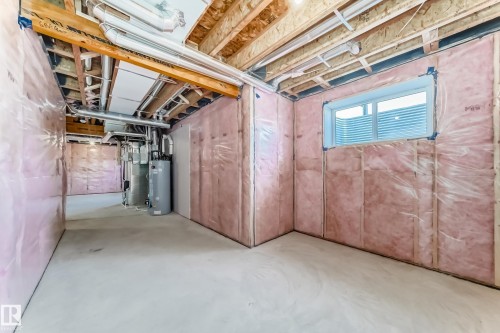 Spacious unfinished basement with insulation, exposed ceiling joists, and a window providing natural light - 840 Stillwater Boulevard, Edmonton, AB - Indoor Photo Showing Basement