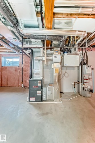 The property features a utility area with exposed ductwork, a furnace, and a water heater, all situated on a concrete floor - 840 Stillwater Boulevard, Edmonton, AB - Indoor Photo Showing Basement