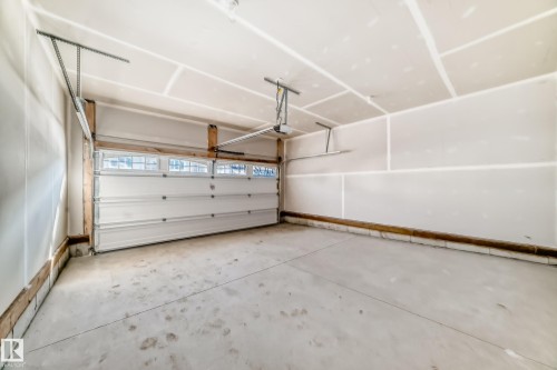 An interior view of the garage, featuring a white sectional door with windows and a concrete floor - 840 Stillwater Boulevard, Edmonton, AB - Indoor Photo Showing Garage