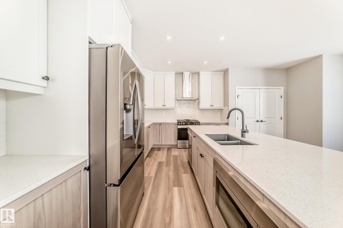 The property features a kitchen with light-toned cabinetry, light countertops, and a stainless steel refrigerator - 840 Stillwater Boulevard, Edmonton, AB - Indoor Photo Showing Kitchen With Double Sink With Upgraded Kitchen
