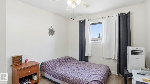 Light-filled room featuring a ceiling fan, a window with exterior views, and wood-finish flooring - 12 14120 80 Street, Edmonton, AB - Indoor Photo Showing Bedroom
