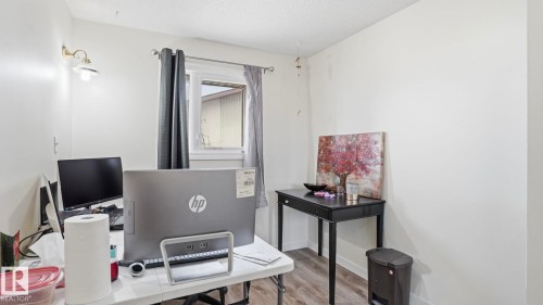 Room featuring a window with privacy curtains, white painted walls, and wood-finish flooring - 12 14120 80 Street, Edmonton, AB - Indoor