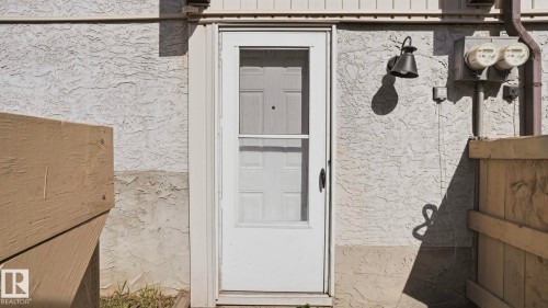 White exterior door with a screen door entry, featuring a black wall-mounted lantern light fixture - 12 14120 80 Street, Edmonton, AB - Outdoor With Exterior