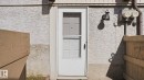 White exterior door with a screen door entry, featuring a black wall-mounted lantern light fixture - 12 14120 80 Street, Edmonton, AB  - Outdoor With Exterior 