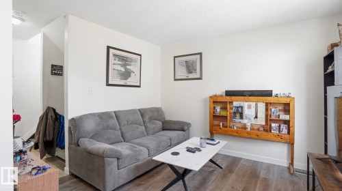 Living area featuring wood-finish flooring, white walls, and a built-in wood-frame shelving unit - 12 14120 80 Street, Edmonton, AB - Indoor Photo Showing Living Room