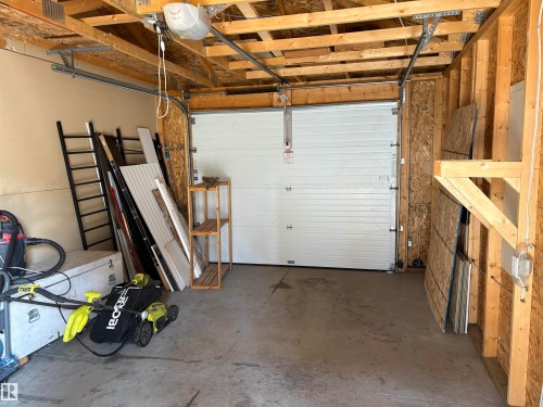 The property features an attached garage with a concrete floor, a white overhead garage door, and exposed wooden framing - 10231 163 Street, Edmonton, AB - Indoor Photo Showing Garage