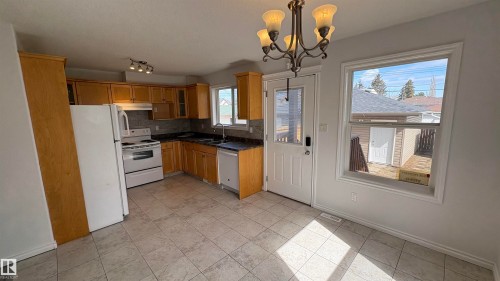 The kitchen features extensive wooden cabinetry, a white refrigerator, and a white oven - 10231 163 Street, Edmonton, AB - Indoor Photo Showing Kitchen With Double Sink