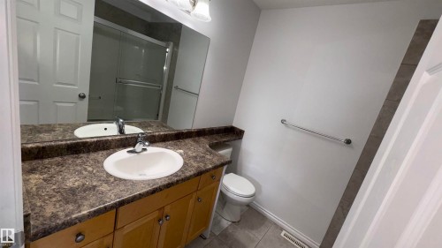 The bathroom features a vanity with light wood cabinetry, a patterned countertop, and an oval sink - 10231 163 Street, Edmonton, AB - Indoor Photo Showing Bathroom