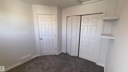 This room features light-colored walls, grey carpet, a white paneled door, and bi-fold closet doors - 10231 163 Street, Edmonton, AB - Indoor Photo Showing Other Room