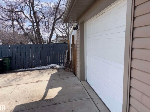 The property features a white panel garage door, tan siding, and a concrete driveway - 10231 163 Street, Edmonton, AB - Outdoor With Exterior