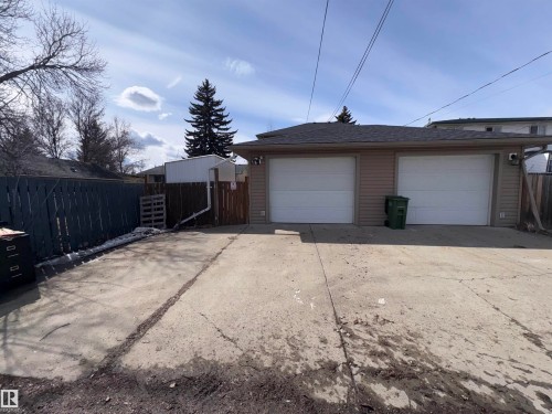 The property features a two-car garage with white garage doors, tan siding, and a dark shingled roof - 10231 163 Street, Edmonton, AB - Outdoor