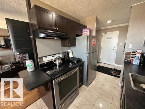 Compact kitchen featuring stainless steel appliances, dark wood cabinetry, and a tile floor - 86 13435 97 Street, Edmonton, AB - Indoor Photo Showing Kitchen