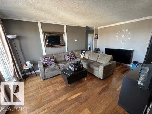 Open-concept living space with wood-finish flooring, neutral wall tones, and crown molding - 86 13435 97 Street, Edmonton, AB - Indoor Photo Showing Living Room