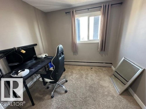 Carpeted room featuring a double-paned window, baseboard heating, and light neutral wall tones - 86 13435 97 Street, Edmonton, AB - Indoor Photo Showing Office