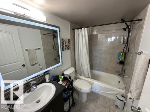 Bathroom featuring a vanity with an undermount sink, a backsplash of mosaic tiles, and an illuminated mirror - 86 13435 97 Street, Edmonton, AB - Indoor Photo Showing Bathroom
