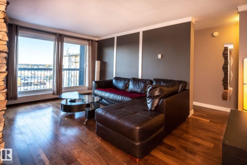 Wood-finish flooring throughout, complemented by a stone-faced column and floor-to-ceiling windows - 86 13435 97 Street, Edmonton, AB - Indoor Photo Showing Living Room
