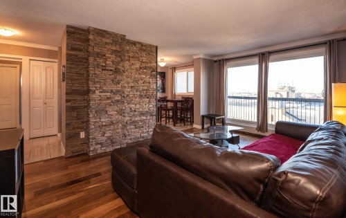 Spacious living area featuring expansive windows, wood-finish flooring, a stacked stone accent wall, and recessed lighting - 86 13435 97 Street, Edmonton, AB - Indoor Photo Showing Living Room