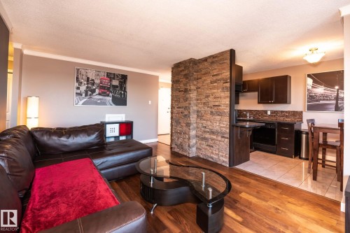 Open-concept living space featuring wood-finish flooring, a stone accent wall, and a tiled kitchen area - 86 13435 97 Street, Edmonton, AB - Indoor Photo Showing Living Room