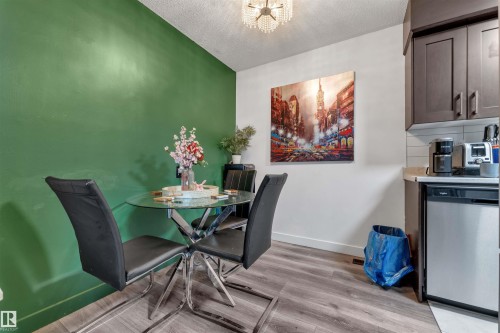 Dining area featuring wood-finish flooring, a vibrant green accent wall, and a crystal chandelier - 7 14115 82 Street, Edmonton, AB - Indoor Photo Showing Dining Room
