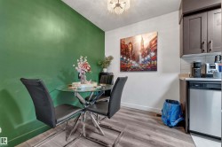 Dining area featuring wood-finish flooring, a vibrant green accent wall, and a crystal chandelier - 