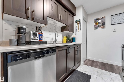 Kitchen with dark wood-finish cabinetry, light-toned countertops, and a white subway tile backsplash - 7 14115 82 Street, Edmonton, AB - Indoor Photo Showing Kitchen With Double Sink