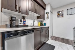 Kitchen with dark wood-finish cabinetry, light-toned countertops, and a white subway tile backsplash - 