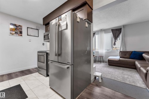 Kitchen area featuring stainless steel appliances including a French door refrigerator, electric range, and built-in microwave - 7 14115 82 Street, Edmonton, AB - Indoor