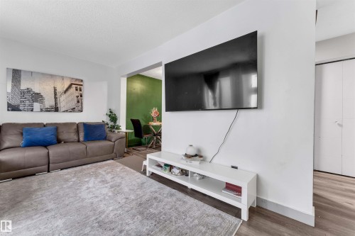 Bright living space featuring light-colored walls and a wall-mounted display - 7 14115 82 Street, Edmonton, AB - Indoor Photo Showing Living Room