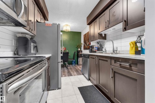 Contemporary kitchen featuring dark wood-finish cabinetry and stainless steel appliances - 7 14115 82 Street, Edmonton, AB - Indoor Photo Showing Kitchen
