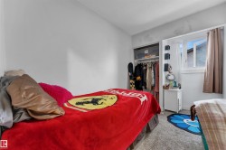 Bedroom featuring light gray walls, textured carpeting, and a window with a white frame - 