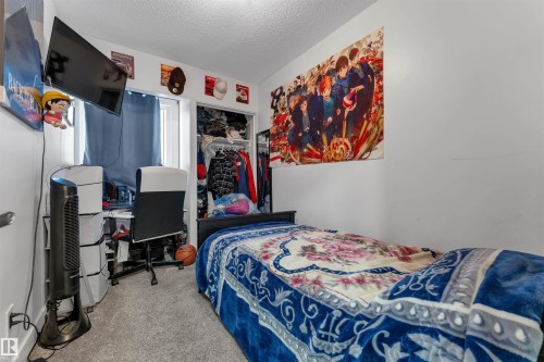 Bedroom featuring light gray wall paint, gray carpet flooring, a window with curtains, and a built-in closet with shelving and hanging space - 7 14115 82 Street, Edmonton, AB - Indoor Photo Showing Other Room
